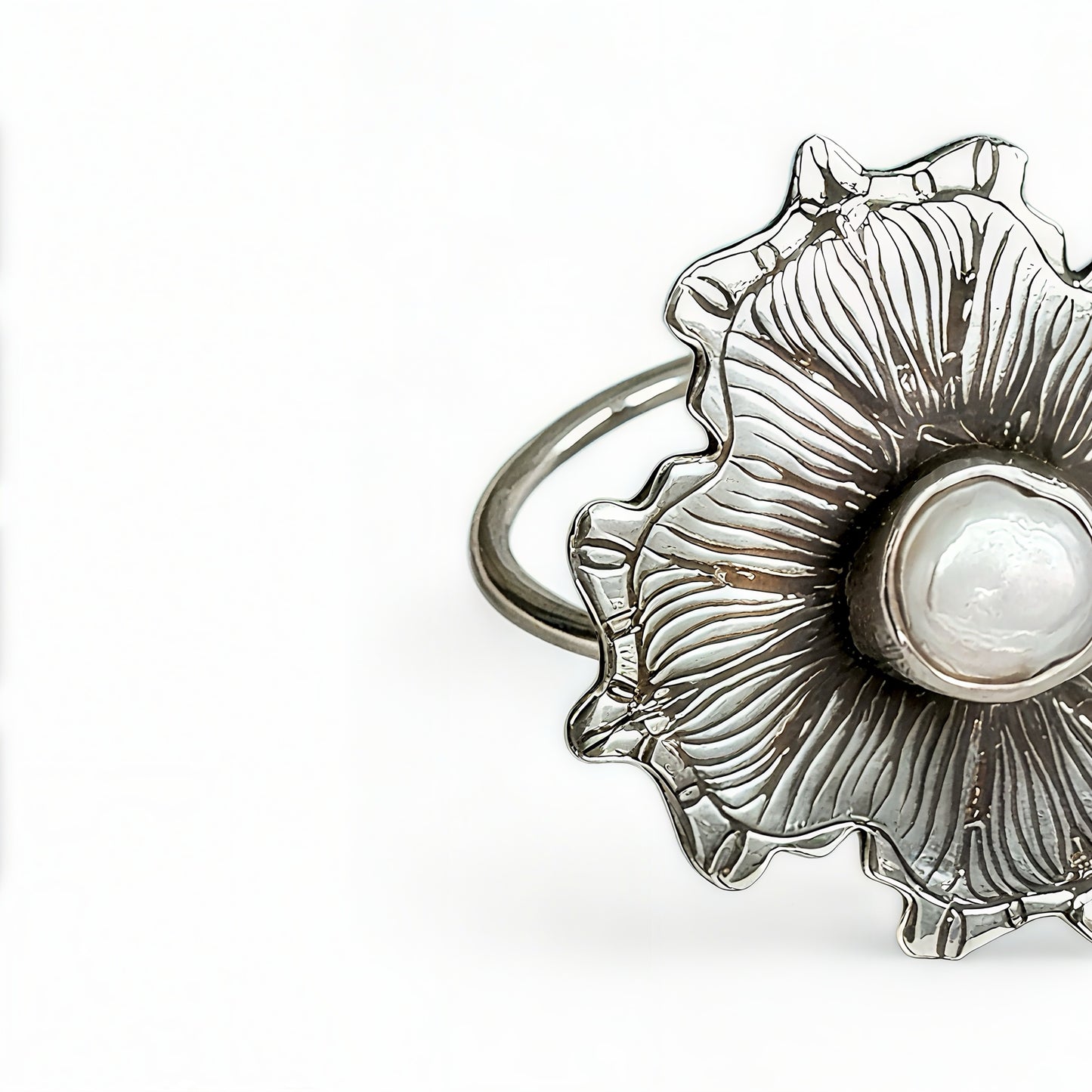 Silver ring with a pearl inside a shell design on a white background