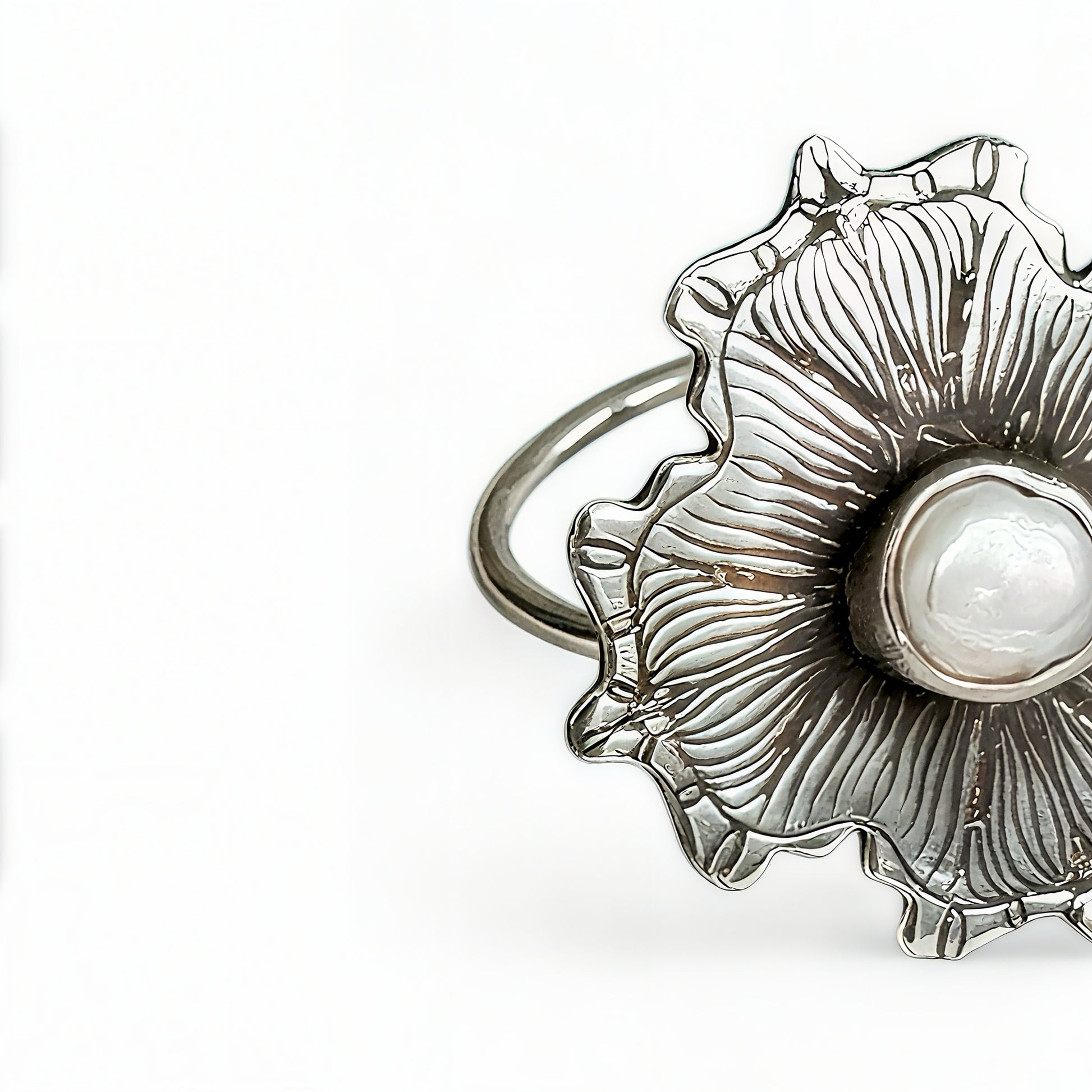 Silver ring with a pearl inside a shell design on a white background