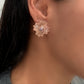 Close-up of a person wearing a rose gold floral earring.