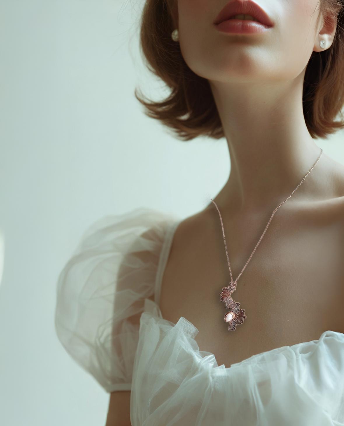 Woman wearing a delicate necklace with a pink pendant against a soft background